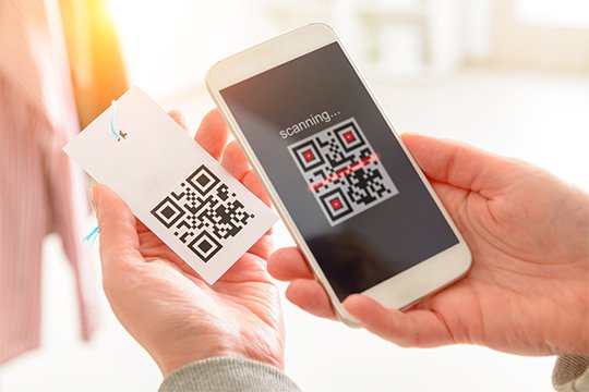 Customer using a smartphone to scan the QR code on a price tag hanging from a men's dress shirt in a retail store